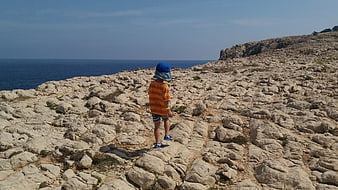 Child hiking on rocky coastal landscape