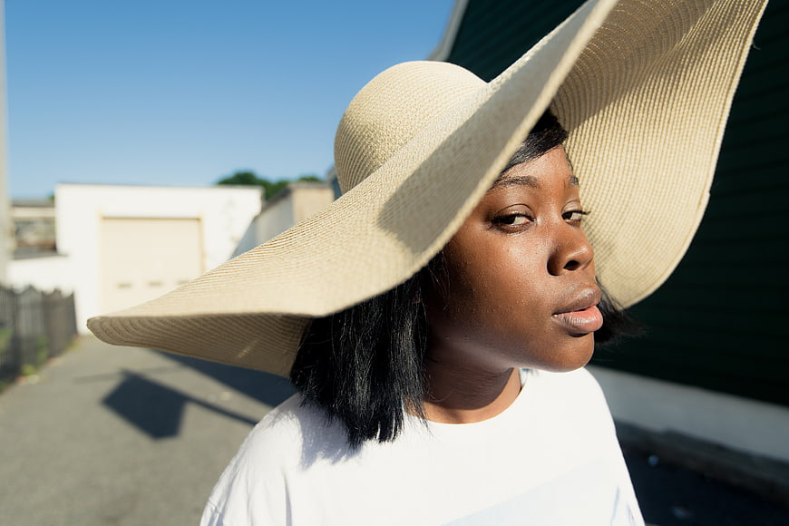 Stylish Black Woman Wearing Oversized Straw Hat Outdoors