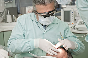Dentist performing procedure with loupes and gloves