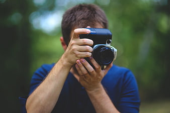Man taking photo with vintage camera in nature