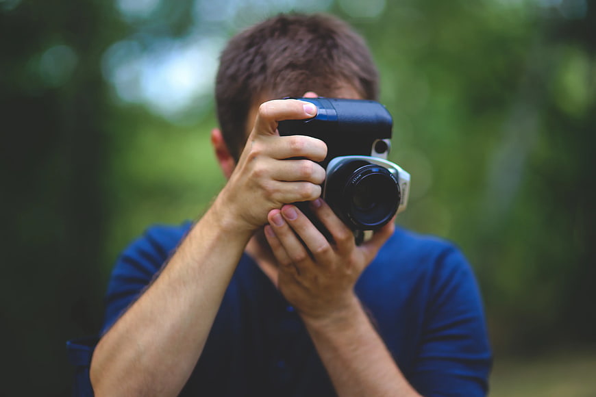 Man taking photo with vintage camera in nature