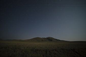 Starry Night Sky Over Rolling Hills and Grassy Field