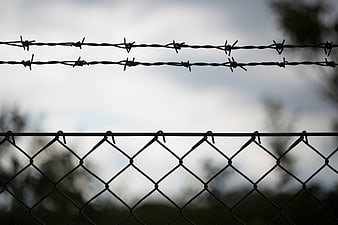 Barbed wire fence silhouette against cloudy sky