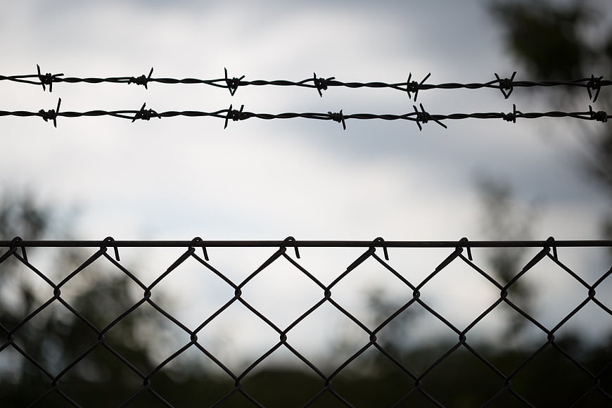 Barbed wire fence silhouette against cloudy sky
