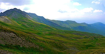 Panoramic Green Mountain Landscape with Rolling Hills and Blue Sky