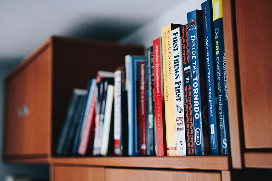 Close-up of books on a wooden shelf with shallow depth of field