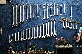 Organized wrenches and tools on blue workshop wall