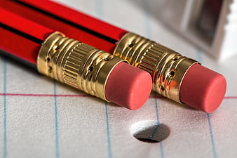Close-up of red pencils with erasers on lined paper