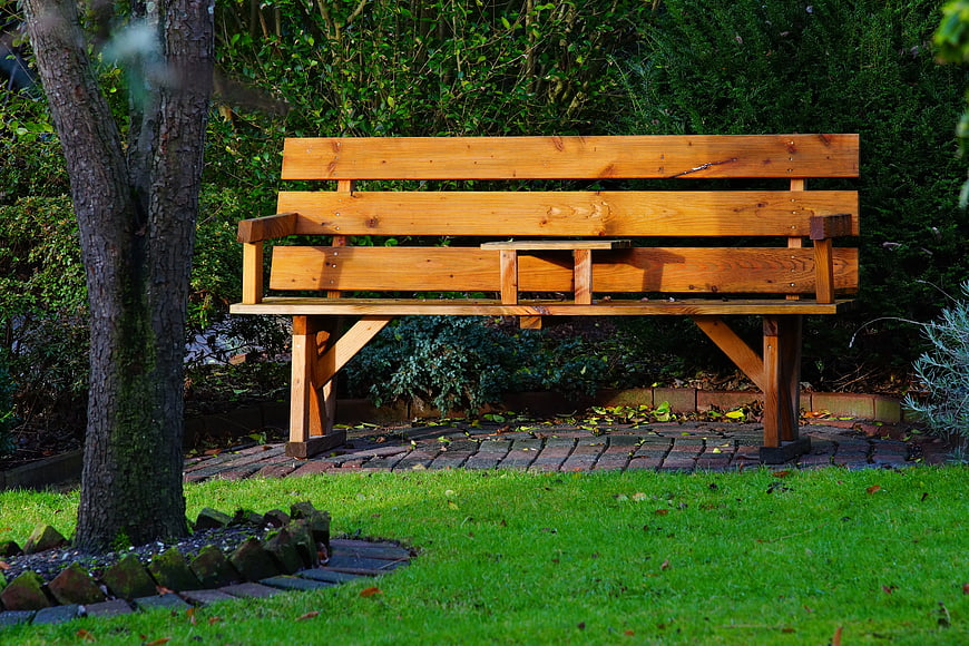 Wooden Garden Bench on Paved Patio with Green Grass