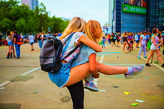 Two women hugging at outdoor color festival event
