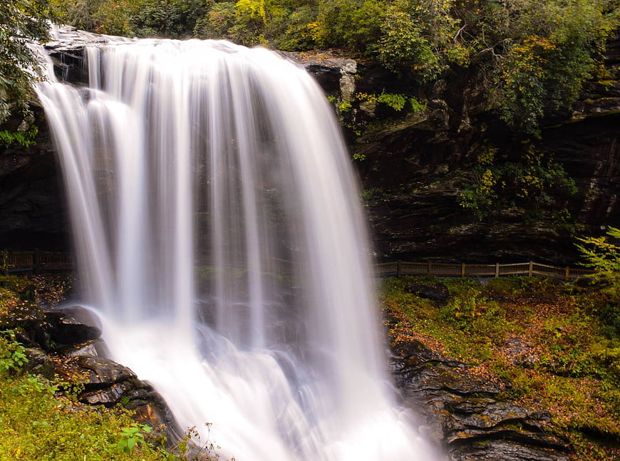 Majestic waterfall cascading through lush autumn forest landscape