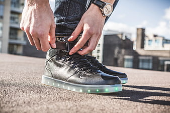 Person adjusting black LED sneakers with glowing soles