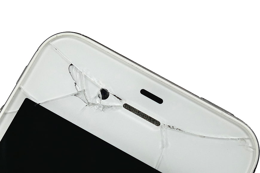 Close-up of cracked white smartphone screen on white background