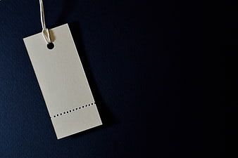 Blank beige paper price tag with string on dark blue background
