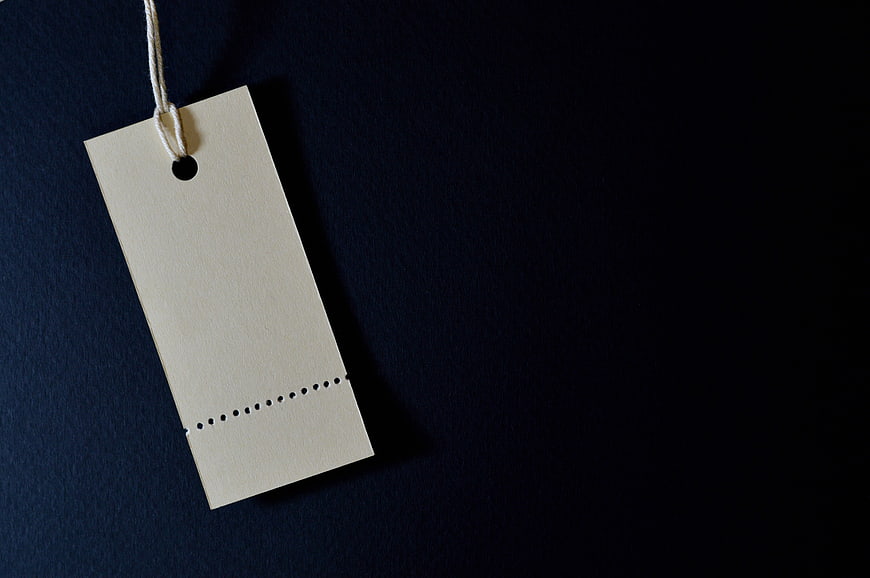Blank beige paper price tag with string on dark blue background