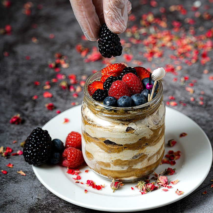 Layered dessert in glass jar topped with fresh berries