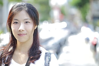 Portrait of smiling Asian woman with backpack outdoors