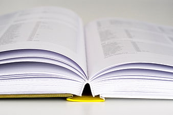 Close-up of open book with yellow bookmark on white background
