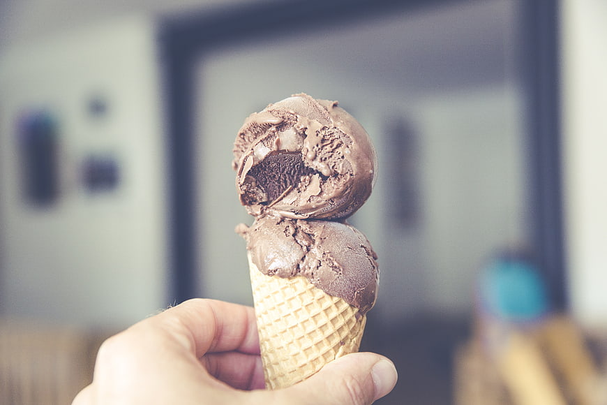 Hand Holding Chocolate Ice Cream Cone with Bite Taken