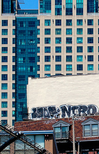 Urban Graffiti on Building Wall with Modern High-Rise Background