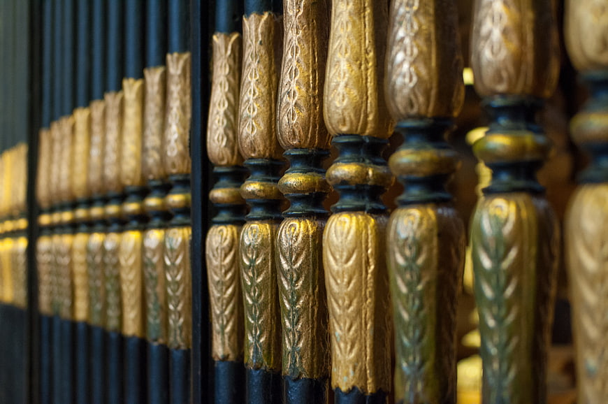 Close-up of ornate golden metal fence with intricate patterns