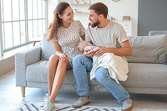 Young Parents Holding Newborn Baby on Sofa