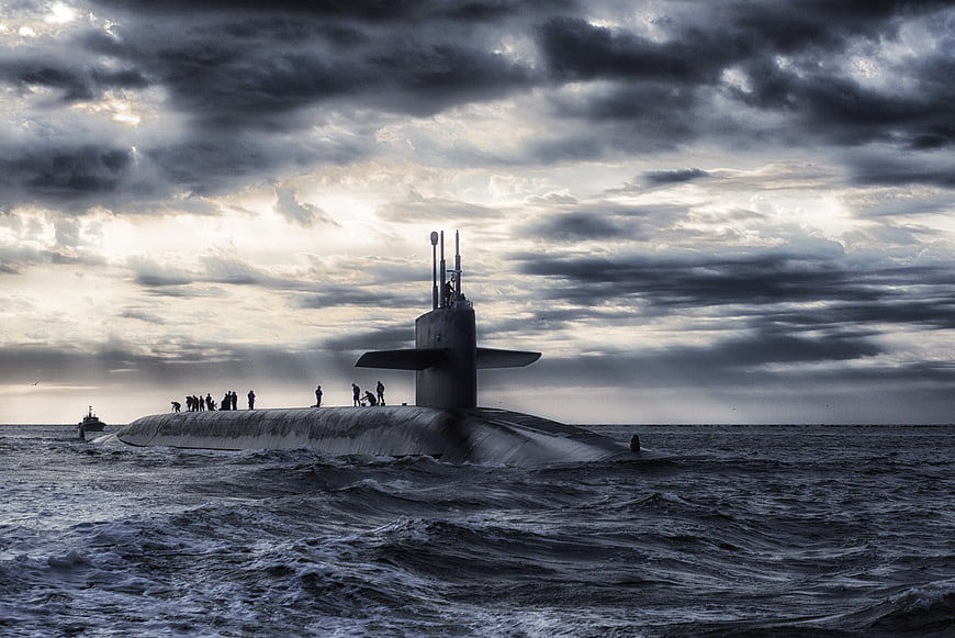Nuclear submarine surfacing in rough ocean under dramatic cloudy sky