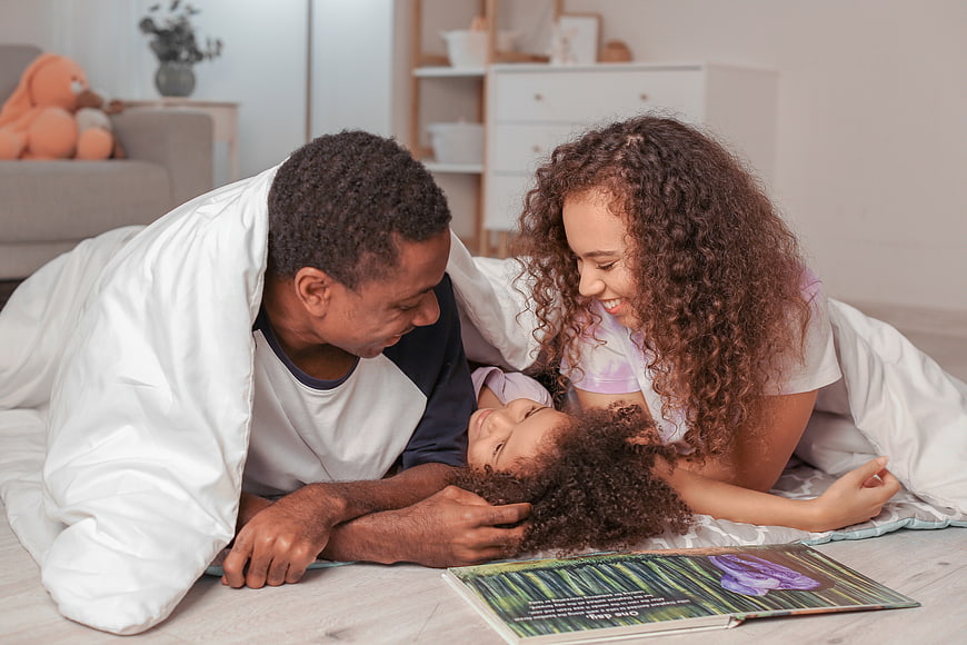 Happy Black Family Reading Together on Floor at Home