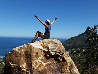 Woman celebrating on mountain peak with ocean view