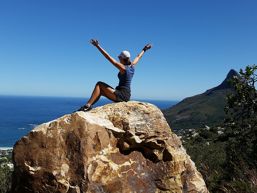 Woman celebrating on mountain peak with ocean view