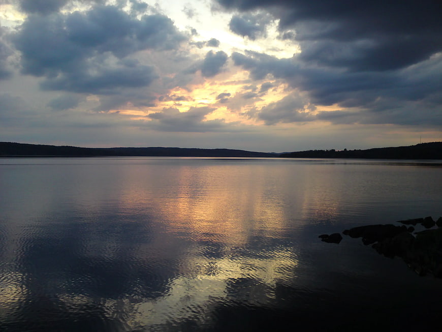 Dramatic sunset over calm lake with golden reflections