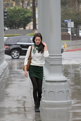 Woman Walking on Wet City Sidewalk in Rain
