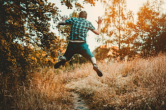 Man jumping in autumn forest path with golden sunlight