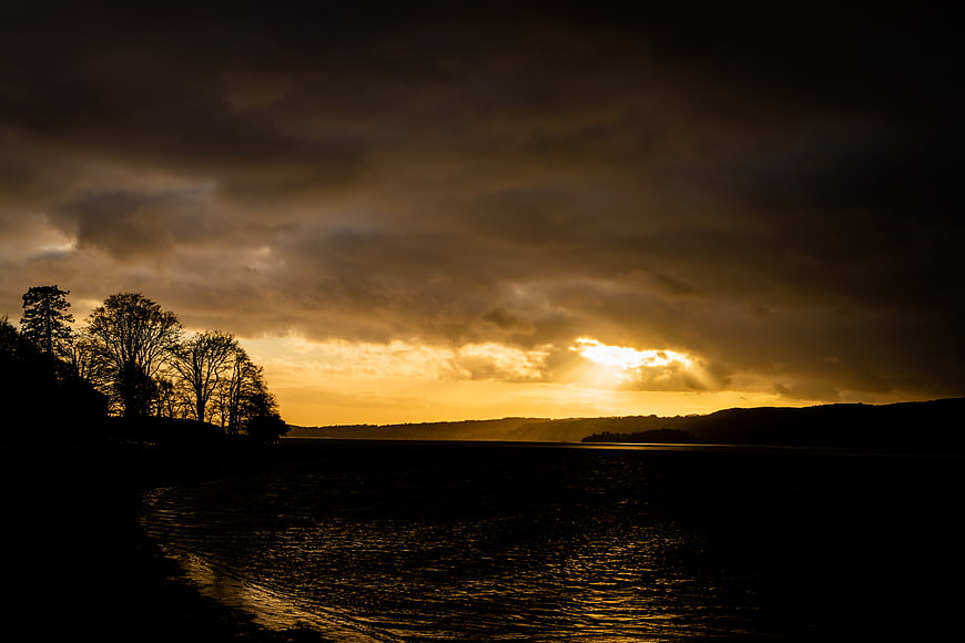 Dramatic Golden Sunset Over Lake with Silhouetted Trees