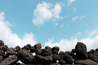 Volcanic Basalt Stone Wall Against Blue Sky With Clouds