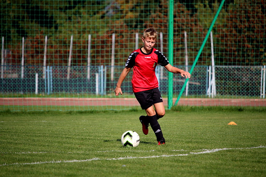 Young boy playing soccer on grass field