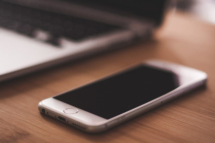 White Smartphone and Laptop on Wooden Desk