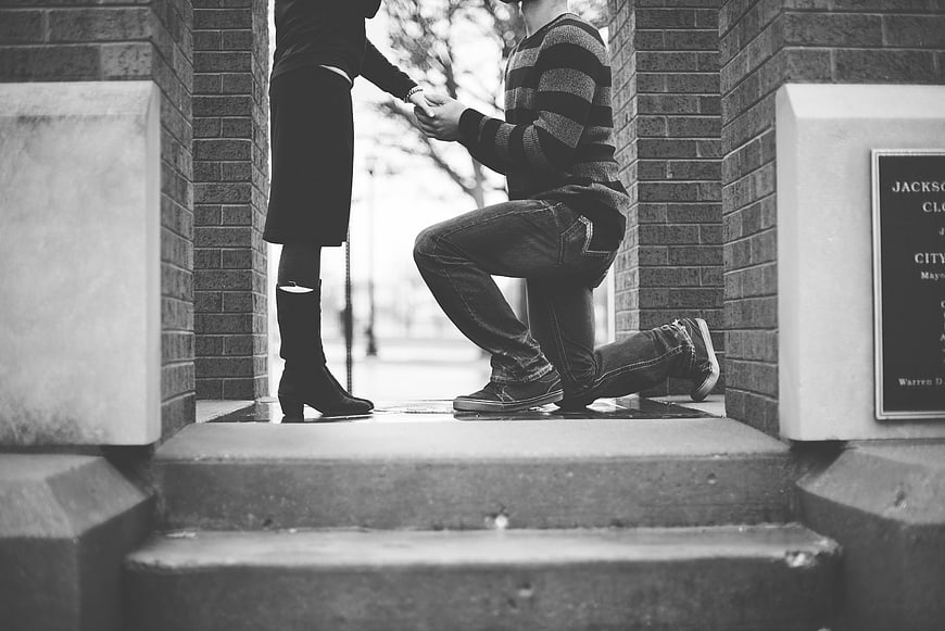 Black and white photo of a man proposing to a woman on steps