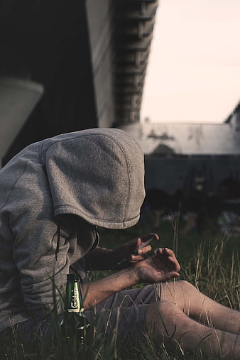Man in Hoodie Preparing Syringe Under Bridge