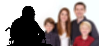 Silhouette of man in wheelchair facing blurred family
