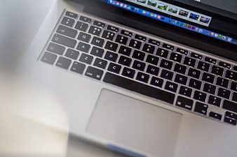 Close-up of MacBook keyboard and trackpad with blurred screen