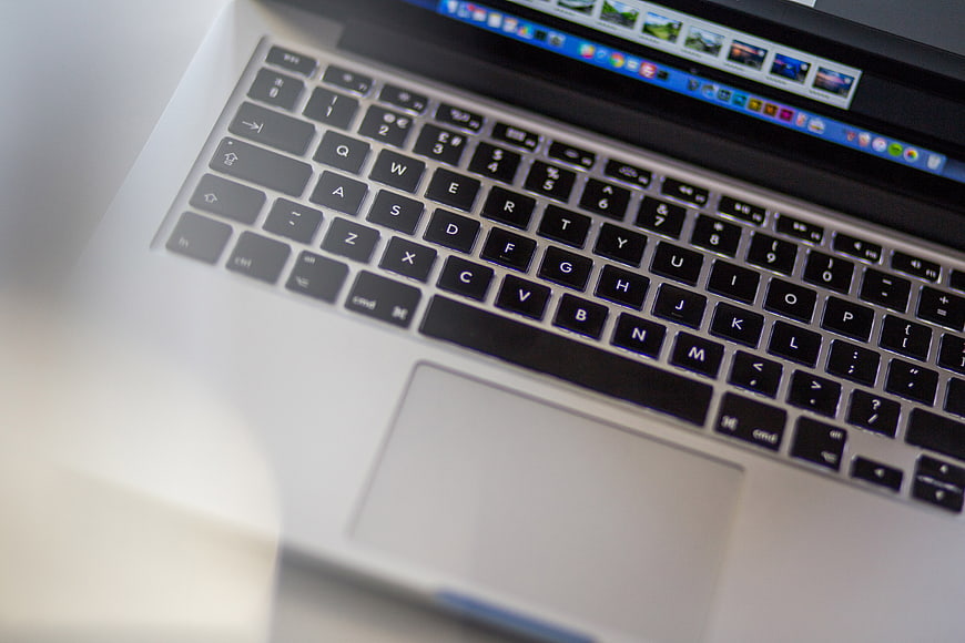 Close-up of MacBook keyboard and trackpad with blurred screen