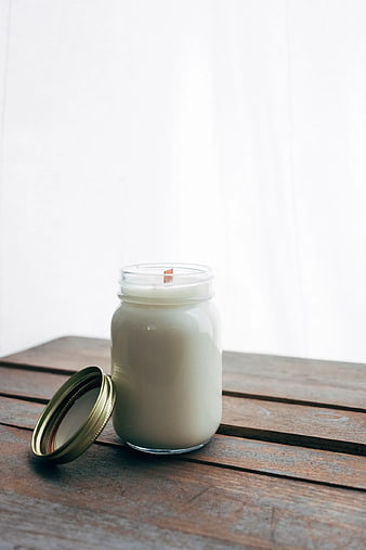White Soy Candle in Glass Jar on Wooden Table