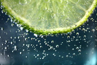 Close-up of lime slice in sparkling water with bubbles