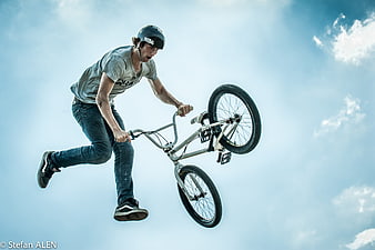 BMX Rider Performing Aerial Stunt Against Blue Sky