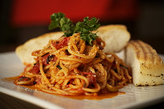Spaghetti with tomato sauce, cheese, and bread on a white plate