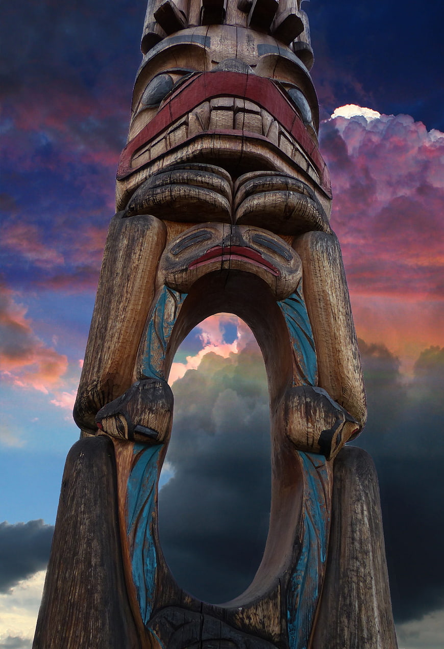 Dramatic Totem Pole Sculpture Against Colorful Sunset Sky