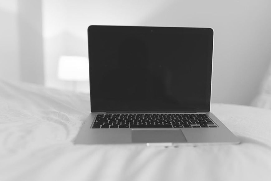 Minimalist Black and White Laptop on White Bed