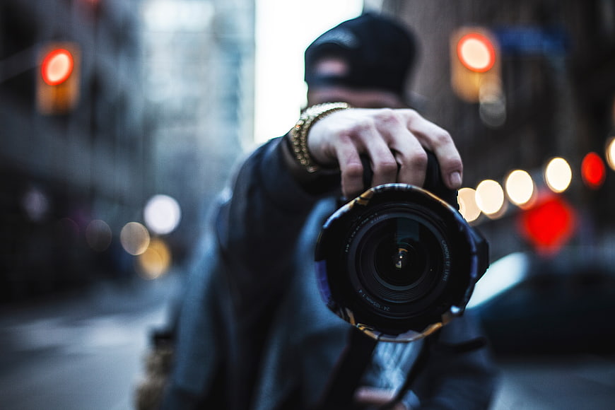 Urban Photographer Holding Camera Lens Towards Viewer