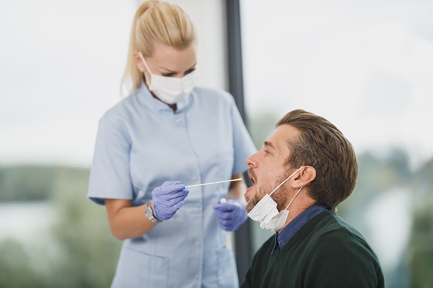 Nurse performing nasal swab test on male patient